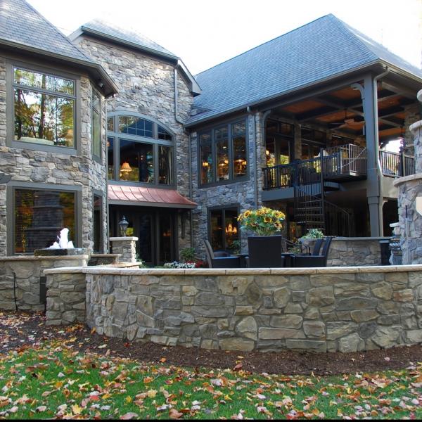 An outdoor stone patio features a fireplace, fountain and ample seating with a spiral staircase leading to a balcony.