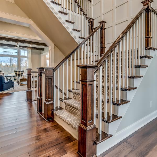 A wood-accented staircase leads from basement to second floor, surrounded by beautiful hardwood floors.