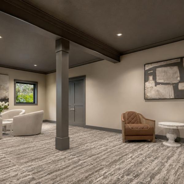 Finished walkout basement living room featuring dark charcoal ceiling, neutral sectional seating, built-in bookshelves, and sliding patio doors.