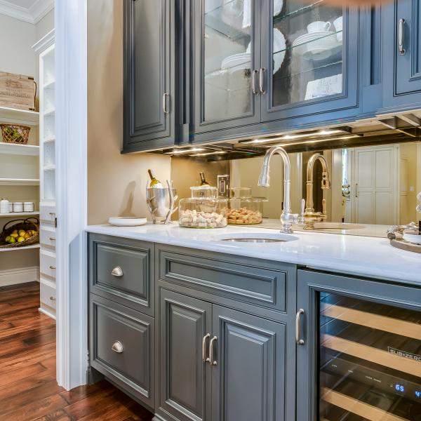 A built-in bar has ample storage with cabinets and a wine fridge, as well as a mirrored bar back enlarging the small space.