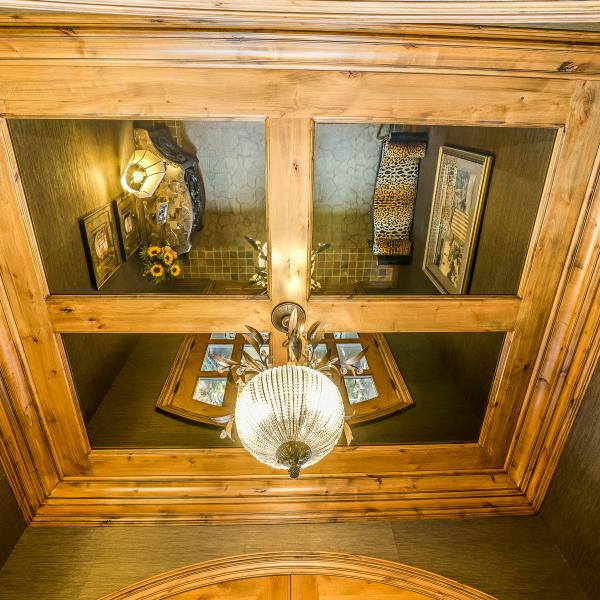 Mirrors installed in the ceiling of a foyer reflects the lighting and makes the small space feel and appear much larger.