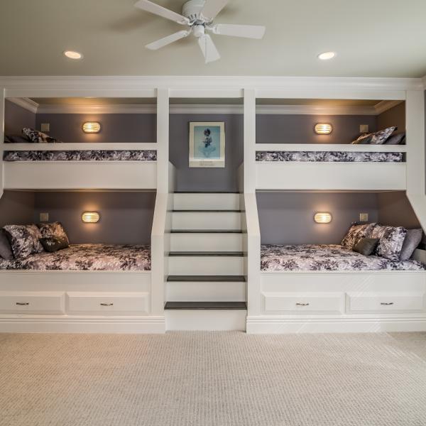 A set of built-in bunk beds features a staircase and storage in a large custom-built family home.