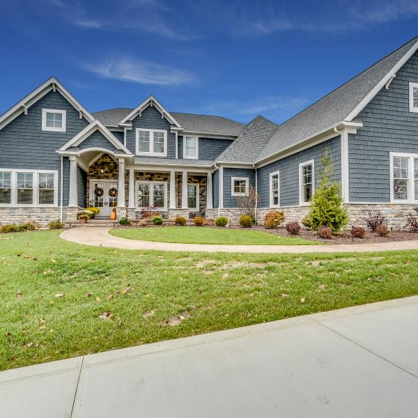 Custom-built home featuring a stone foundation, stone entryway with French doors and gray-blue shake and shingle siding.