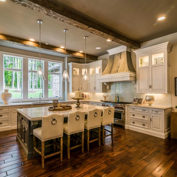 Custom-built kitchen with high ceilings featuring wood beams, modern appliances, ample storage, and beautiful countertops.