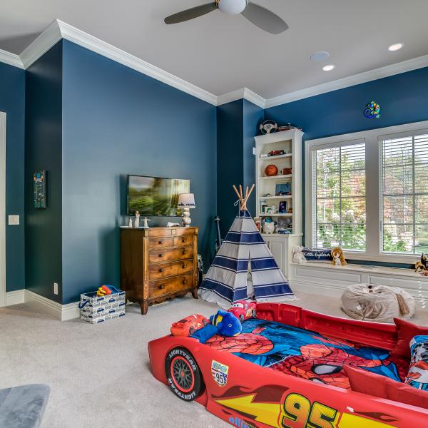 A children’s room featuring built-in shelving surrounding a large window in a custom-built home.