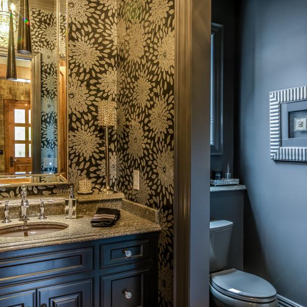 A bathroom featuring modern wallpaper and fixtures with a sink-to-ceiling length mirror.