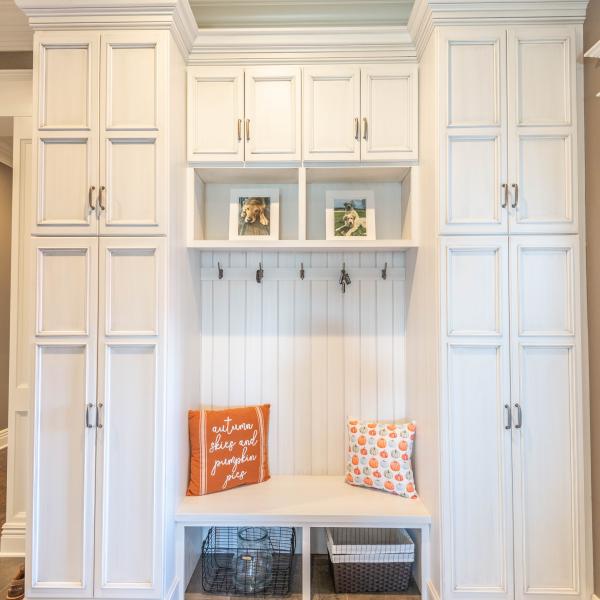 Built-in storage featuring clean white paint and hooks for hanging coats and a bench for putting on and removing shoes.